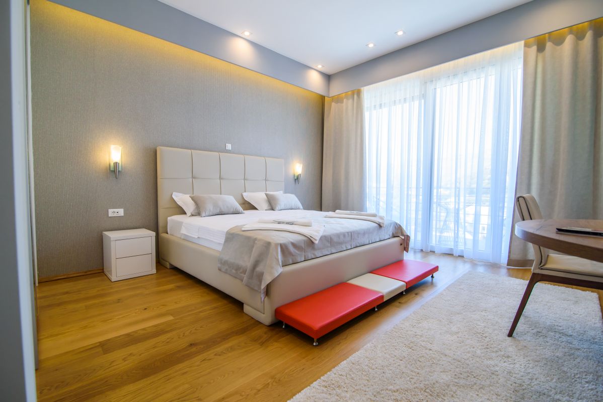 large bedroom with wood floors and an upholstered bed