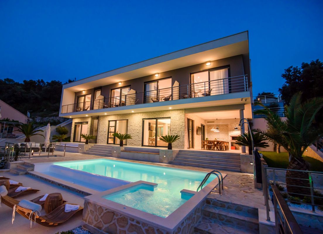 luxury villa exterior with a large pool, shown at night