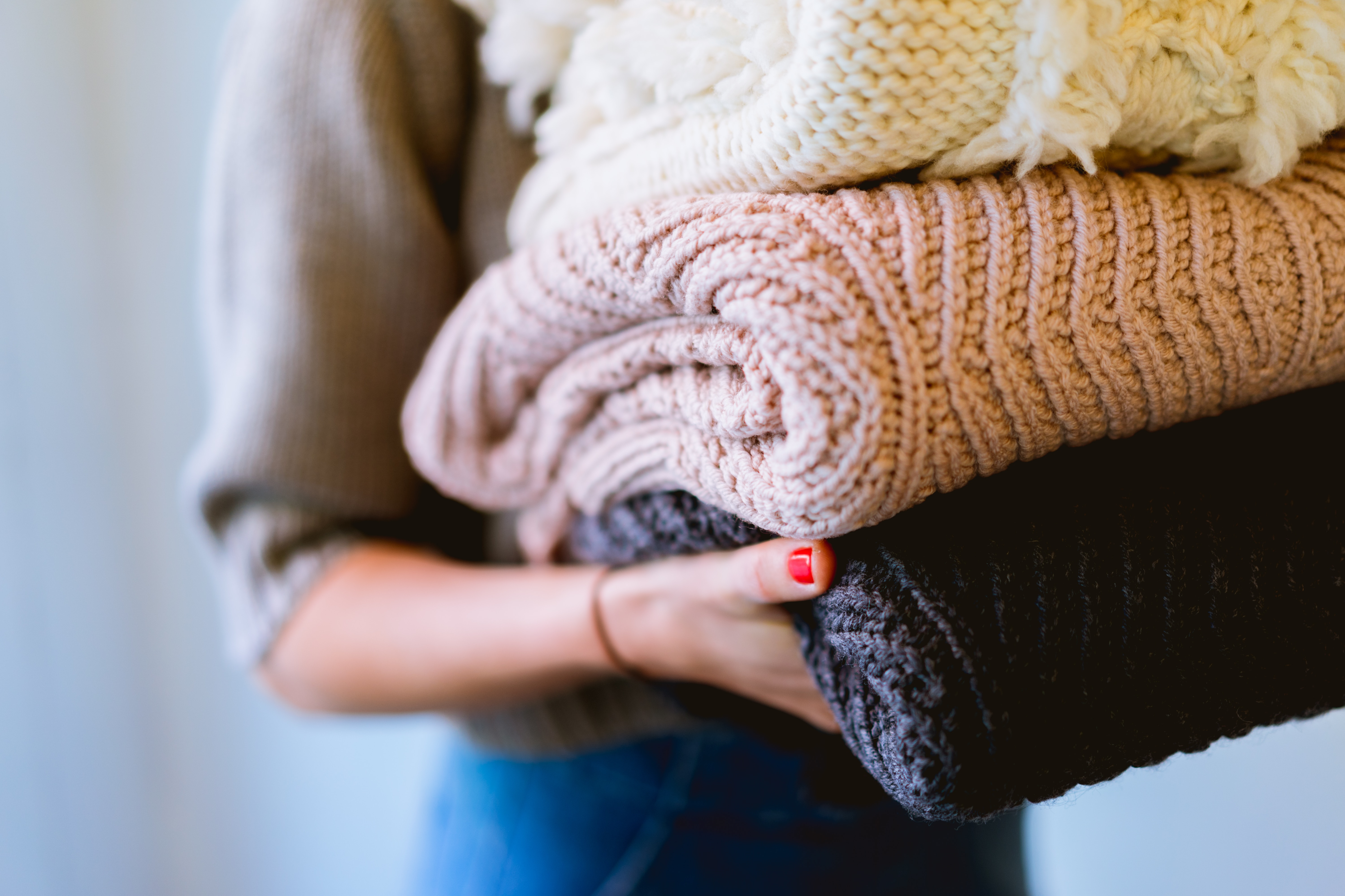 holding pile of folded sweaters