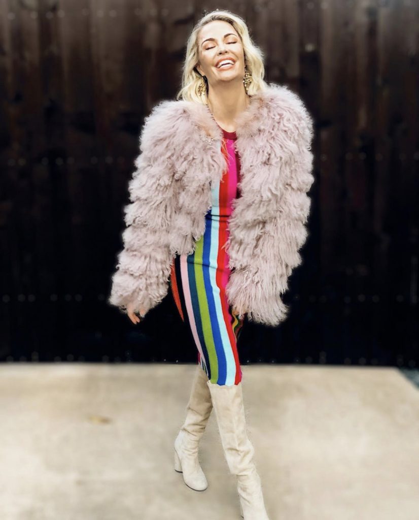 Whitney smiling in colorful, striped dress and faux fur coat